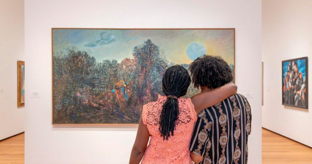 Dos visitantes observando juntas una pintura dentro de una galería.